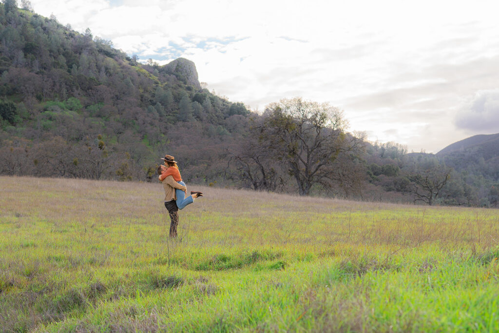 Couple in an open field near a rustic water tower with the summit of Mt. Diablo in the background in the Bay Area, California