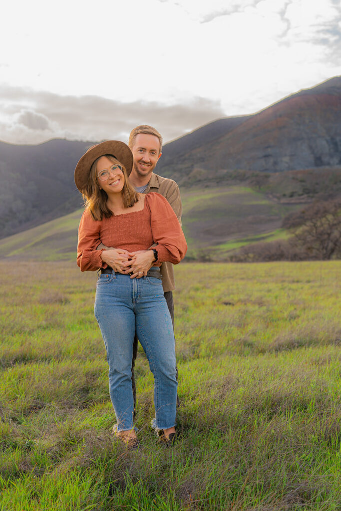 Couple together in an open field with the mountains of Clayton, California, in the background